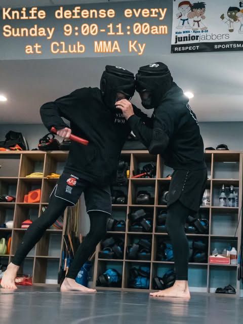 Knife-defense training with protective headgear and a red training knife at Club MMA